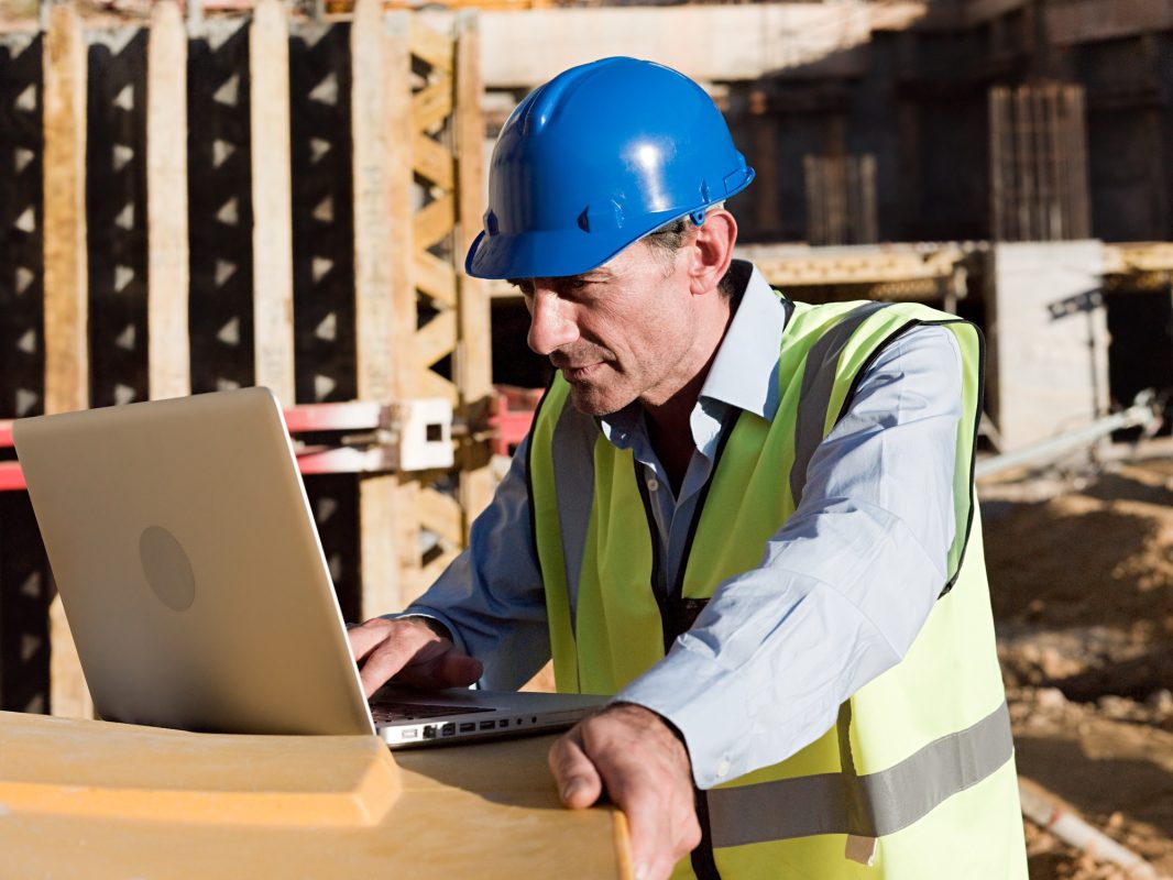 Mature man using laptop on construction site