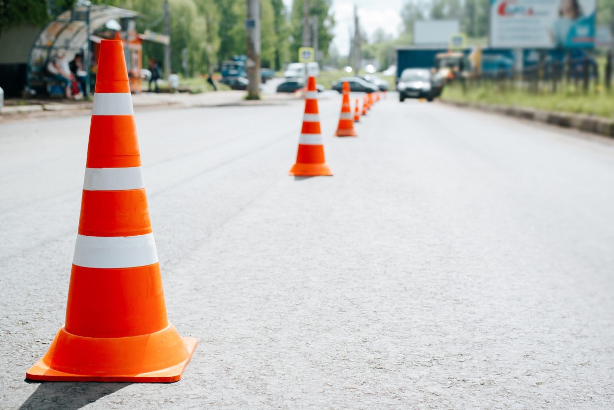 Traffic safety cones on asphalt of road. Selective focus on striped orange-white warning signs